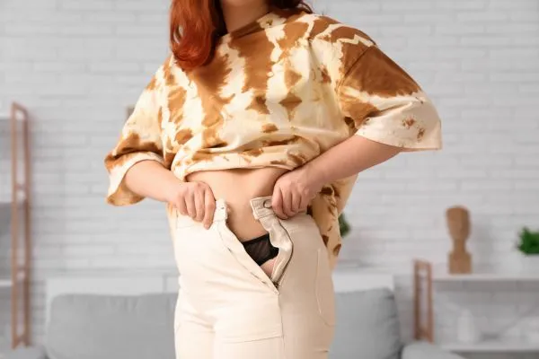 Image of woman trying to do her trousers up after pregnancy weight gain Central Milton Keynes